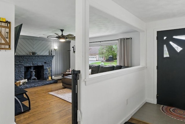 735 Union St, Leominster, MA 01453 - foyer entrance with wood finished floors, a baseboard heating unit, ceiling fan, a stone fireplace, and baseboards
