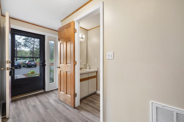 entryway featuring light wood-style flooring, a sink, and crown molding