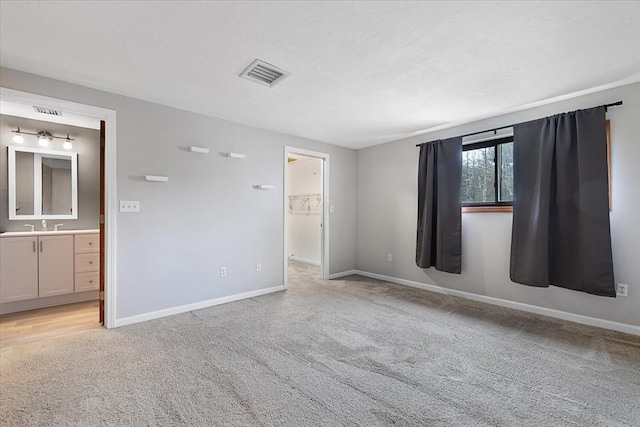 empty room featuring light colored carpet, baseboards, and a sink