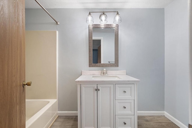 full bath featuring wood finished floors, baseboards, and vanity