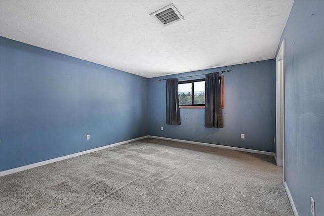 carpeted spare room with a textured ceiling and baseboards