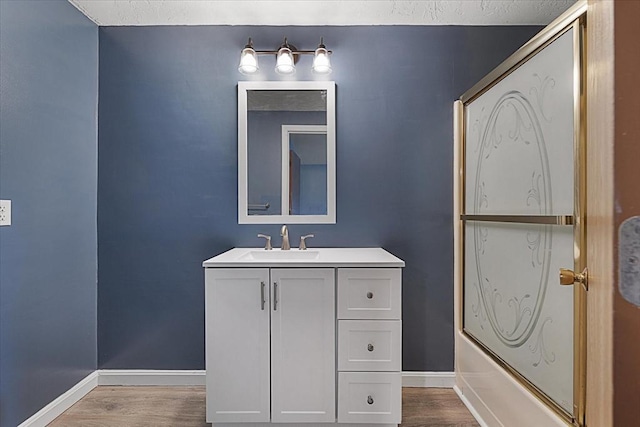 full bath featuring wood finished floors, baseboards, vanity, and bathing tub / shower combination