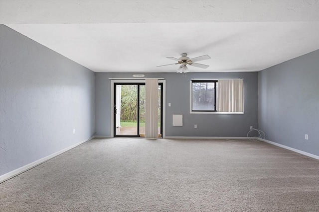 carpeted empty room with plenty of natural light, ceiling fan, and baseboards