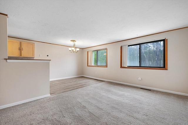 unfurnished room with light colored carpet, a chandelier, baseboards, and ornamental molding