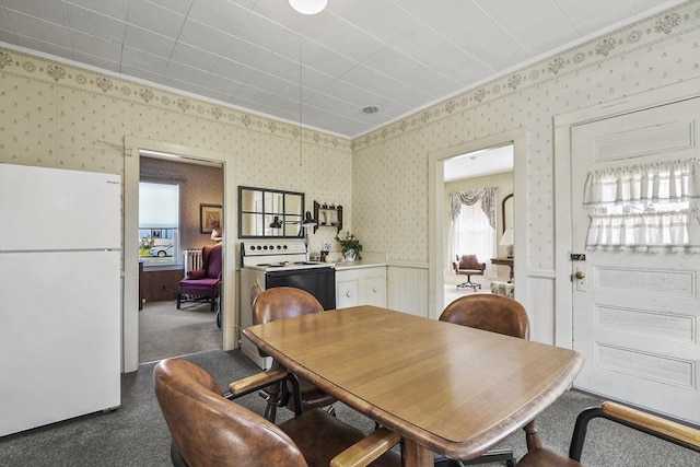 dining room featuring dark colored carpet and wallpapered walls