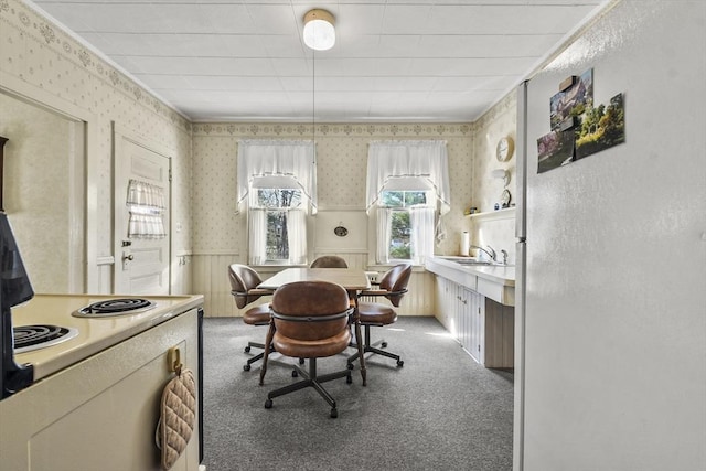 dining room featuring wainscoting, light colored carpet, and wallpapered walls