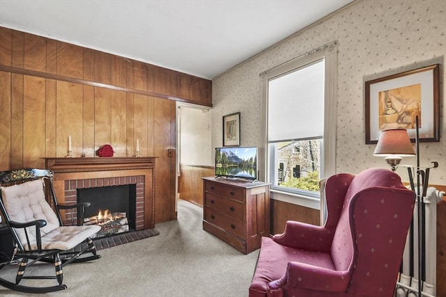 sitting room featuring wallpapered walls, wooden walls, a brick fireplace, and carpet