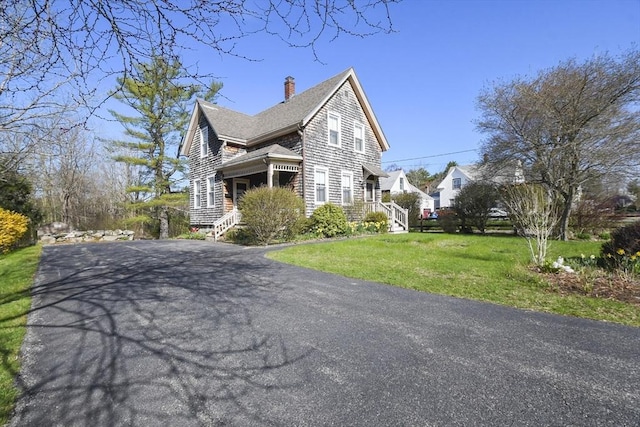 view of property exterior featuring a chimney, roof with shingles, driveway, and a yard