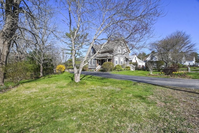 view of front facade with driveway, a front lawn, and covered porch