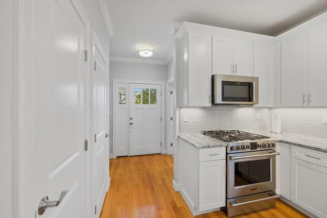 7 Garvey Rd Unit 7, Woburn, MA 01801 - kitchen featuring stainless steel appliances, ornamental molding, tasteful backsplash, white cabinets, and light stone counters