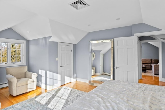 bedroom featuring lofted ceiling, connected bathroom, and light hardwood / wood-style flooring