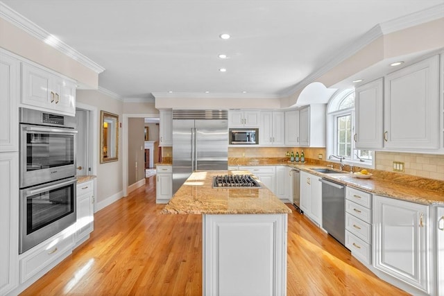 kitchen featuring white cabinetry, built in appliances, light stone counters, tasteful backsplash, and a kitchen island