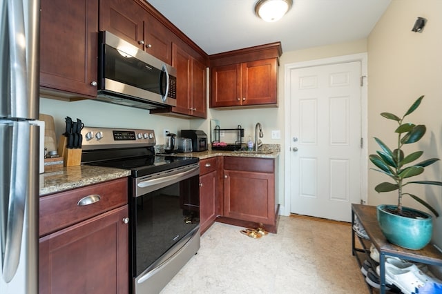 kitchen featuring light stone countertops, stainless steel appliances, and sink