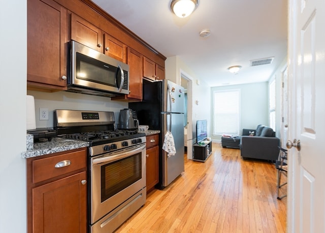 kitchen with light hardwood / wood-style flooring, stainless steel appliances, and dark stone counters