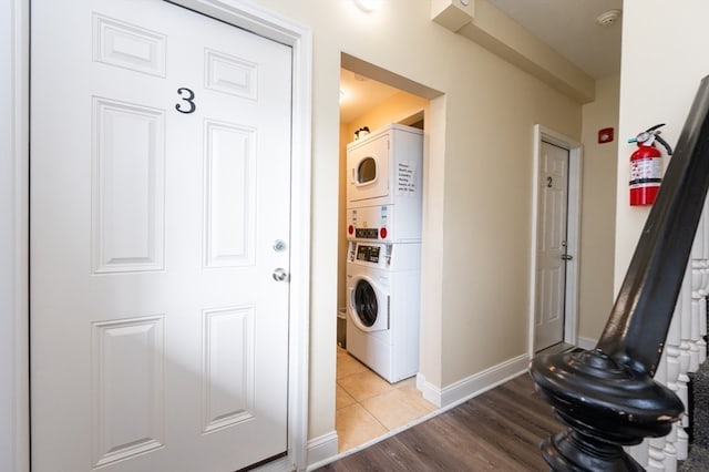 washroom with wood-type flooring and stacked washer / drying machine