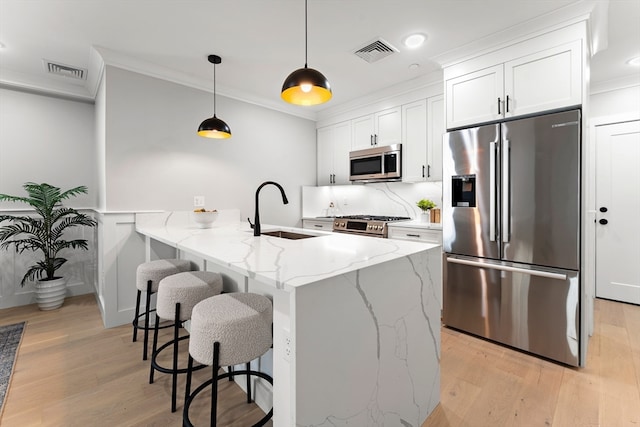 kitchen with light stone counters, sink, white cabinetry, hanging light fixtures, and appliances with stainless steel finishes