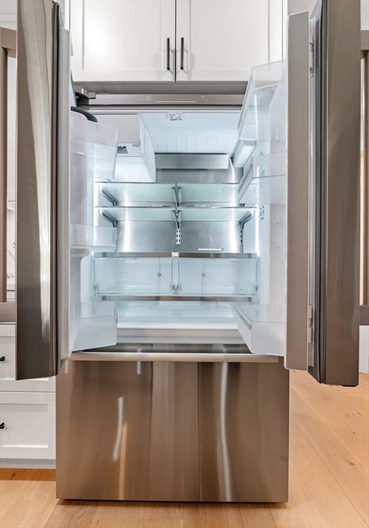 kitchen with white cabinetry, light hardwood / wood-style floors, and stainless steel refrigerator