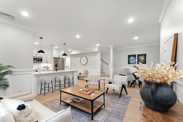 living room with light wood-type flooring and crown molding