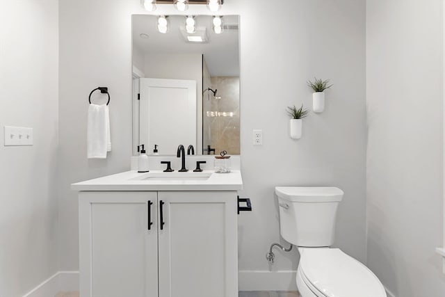 bathroom with a tile shower, vanity, and toilet