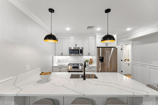 kitchen with pendant lighting, a breakfast bar area, white cabinetry, appliances with stainless steel finishes, and light stone countertops