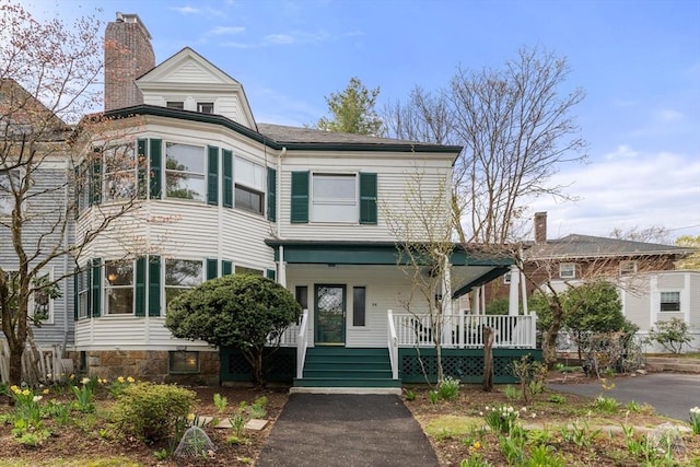 victorian-style house with a porch and a chimney