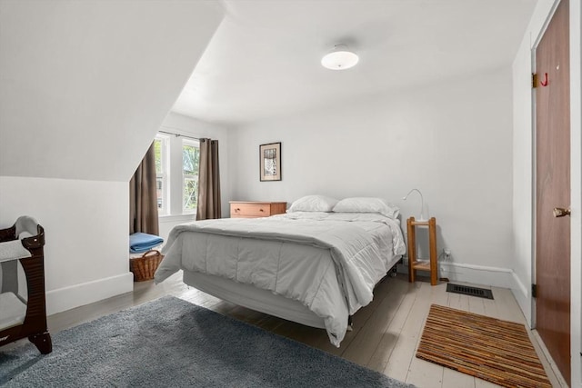 bedroom with baseboards, visible vents, and light wood-type flooring
