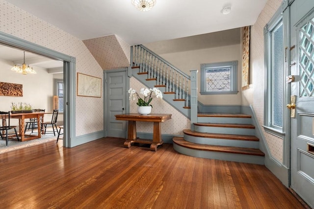 stairs featuring baseboards, wood finished floors, a chandelier, and wallpapered walls
