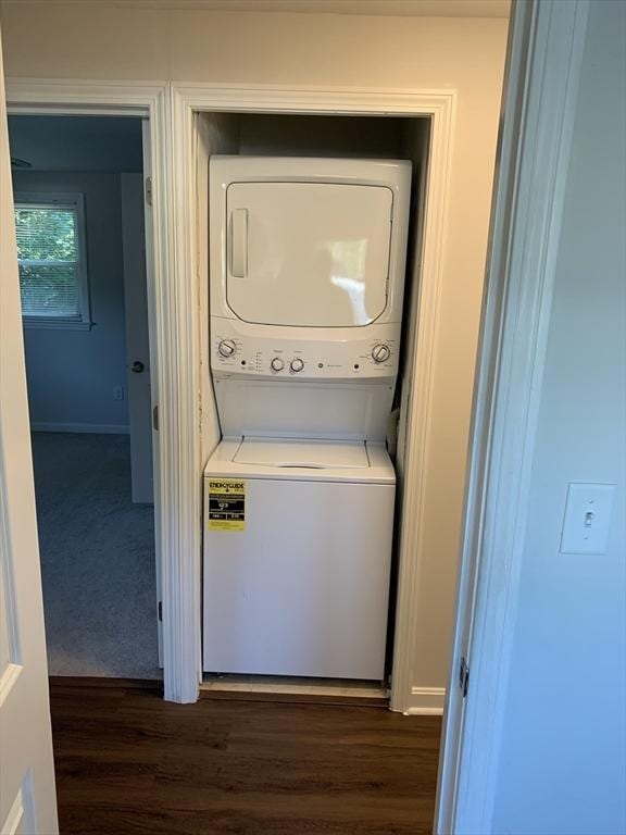 clothes washing area featuring dark hardwood / wood-style flooring and stacked washing maching and dryer