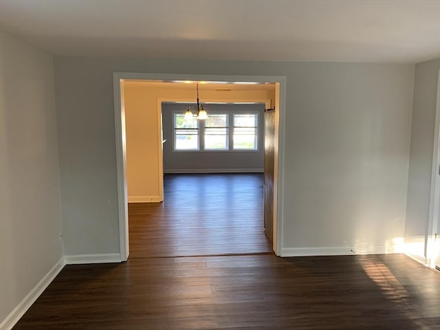 spare room with dark hardwood / wood-style floors and a notable chandelier