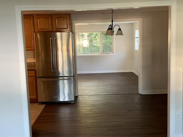 kitchen with a notable chandelier, high end fridge, hanging light fixtures, and dark wood-type flooring