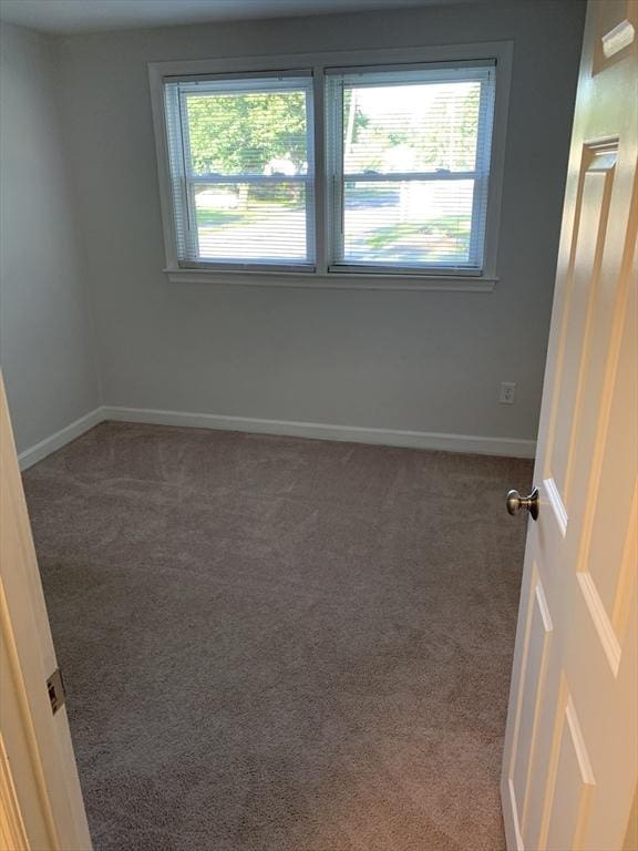 spare room with dark colored carpet