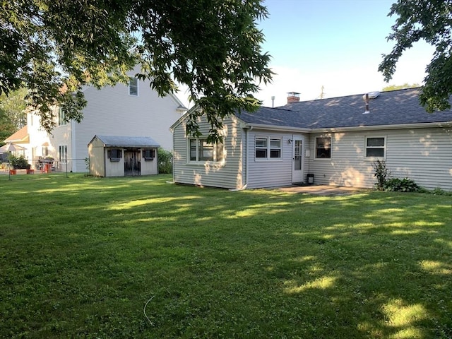 back of property featuring a storage shed and a yard