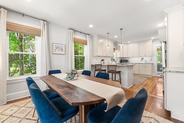 dining room with light wood finished floors, recessed lighting, and baseboards