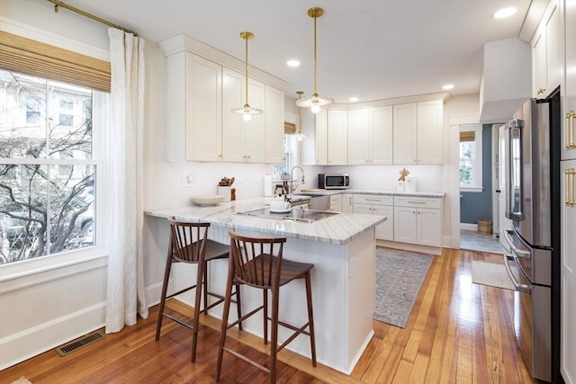 kitchen with stainless steel appliances, a peninsula, white cabinetry, and recessed lighting