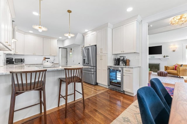 kitchen featuring beverage cooler, appliances with stainless steel finishes, a peninsula, dark wood-style flooring, and white cabinets