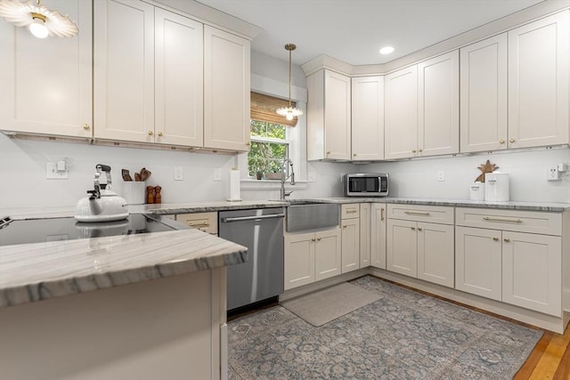 kitchen with stainless steel appliances, recessed lighting, a sink, hanging light fixtures, and light stone countertops