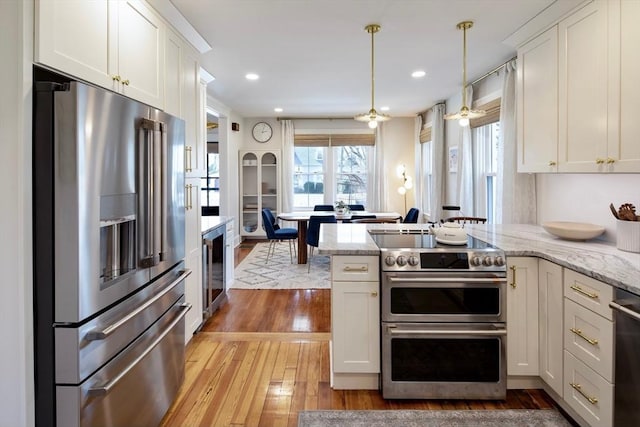 kitchen featuring stainless steel appliances, beverage cooler, light wood-type flooring, a peninsula, and white cabinets