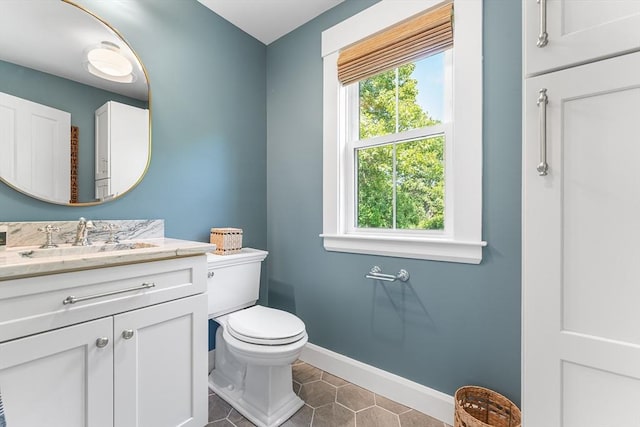 bathroom featuring baseboards, tile patterned flooring, toilet, and vanity