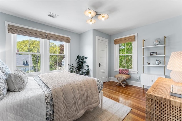 bedroom with radiator heating unit, wood finished floors, and baseboards
