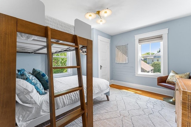 bedroom with wood finished floors, multiple windows, and baseboards