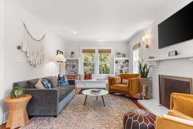 living room with wood finished floors and a brick fireplace