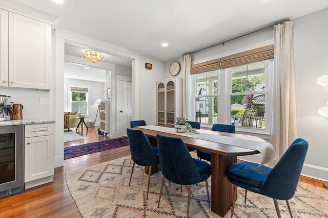 dining area featuring wine cooler, dark wood-type flooring, a bar, recessed lighting, and baseboards