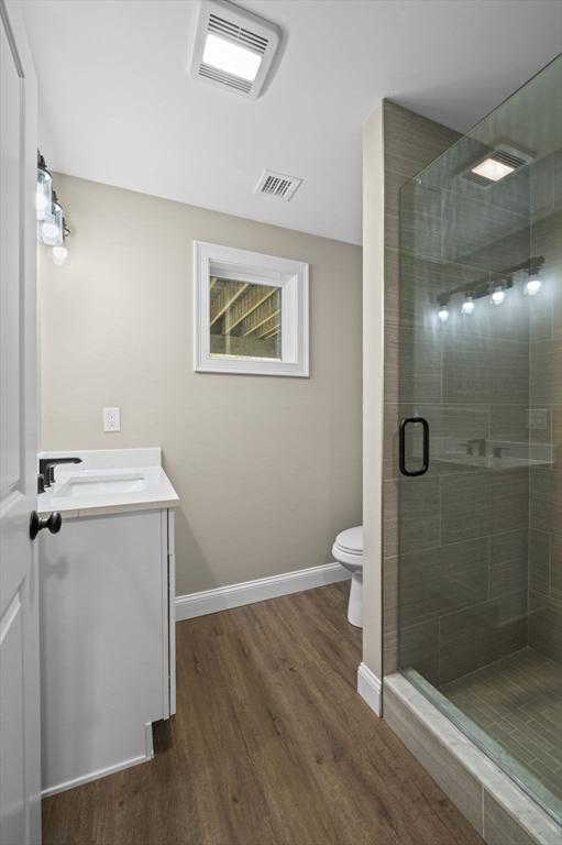 bathroom featuring vanity, hardwood / wood-style floors, walk in shower, and toilet