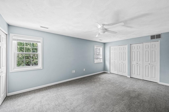 10 Freedom Holw Unit 10, Salem, MA 01970 - unfurnished bedroom featuring two closets, carpet, multiple windows, and a ceiling fan