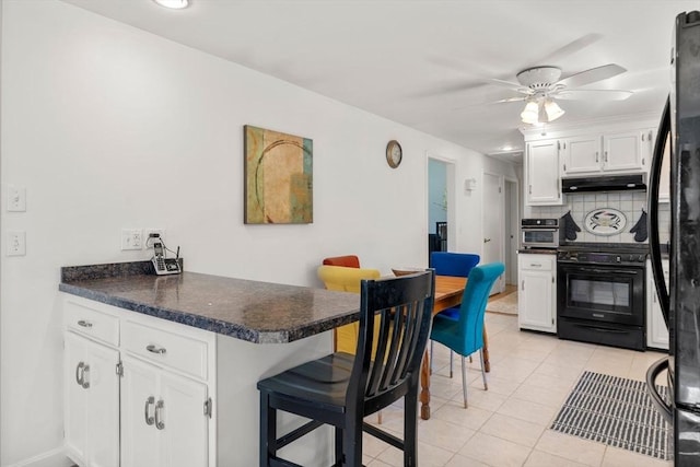kitchen with range, dark countertops, white cabinets, a peninsula, and under cabinet range hood