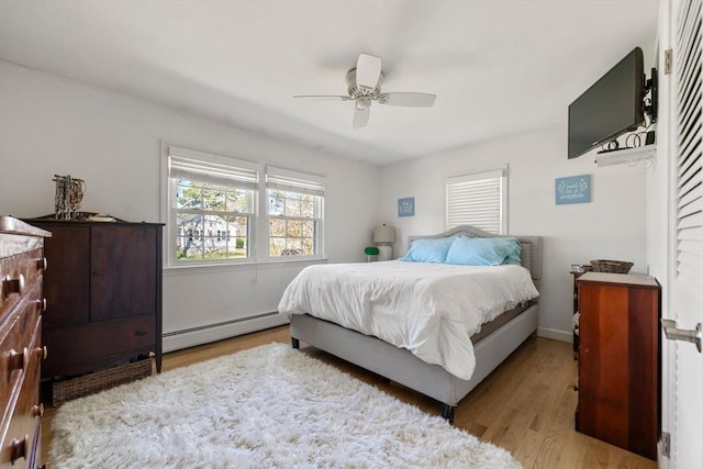 bedroom with a ceiling fan, wood finished floors, and a baseboard radiator
