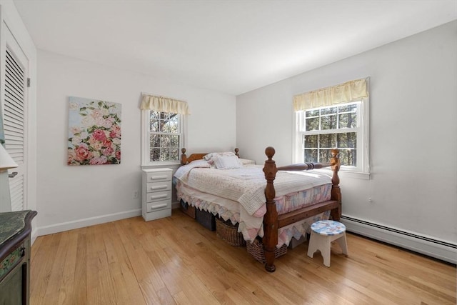 bedroom with baseboards, baseboard heating, and light wood finished floors