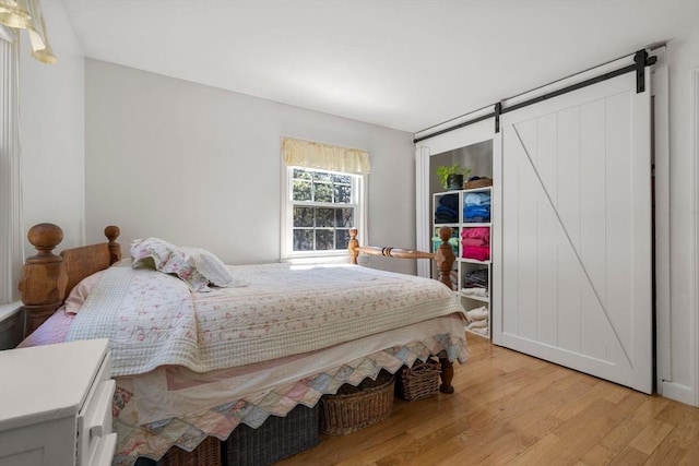 bedroom featuring a barn door and light wood finished floors