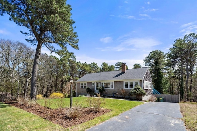 single story home with driveway, a chimney, and a front lawn