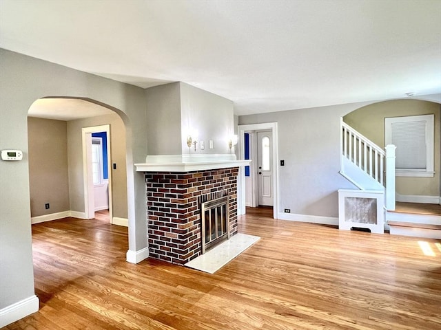 65 Franklin Rd, Longmeadow, MA 01106 - unfurnished living room with light wood finished floors, stairway, arched walkways, and a glass covered fireplace